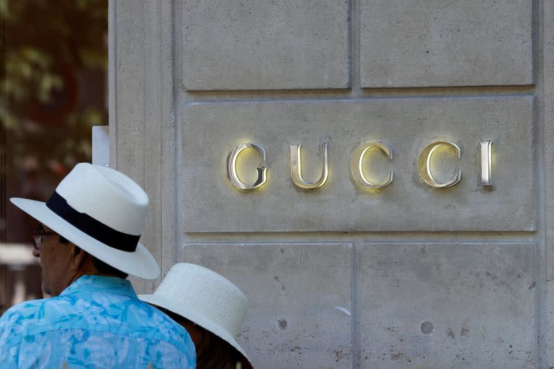 People stand in front of a store of luxury brand Gucci on Avenue Montaigne in Paris