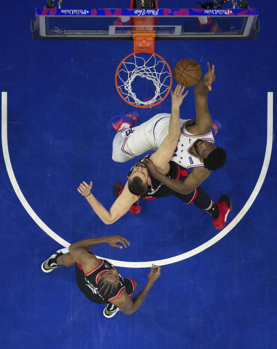 Philadelphia 76ers' Joel Embiid, right, shoots against Toronto Raptors' Marc Gasol, center, with Kawhi Leonard, left, watching during the first half of Game 3 of a second-round NBA basketball playoff series, Thursday, May 2, 2019, in Philadelphia. (AP Photo/Chris Szagola)