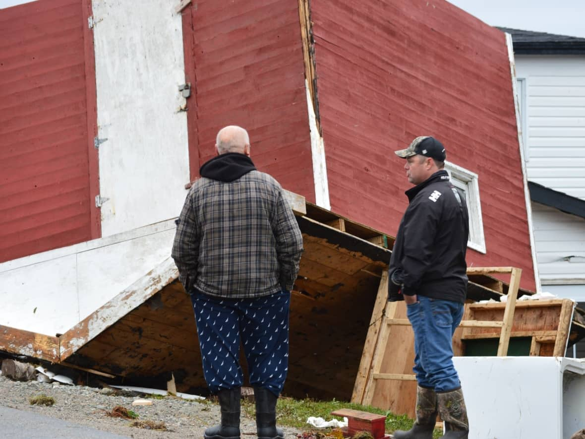 Two men in Port aux Basques survey the devastation of their town. More than 20 homes were destroyed completely, while others suffered catastrophic damage. (Malone Mullin/CBC - image credit)