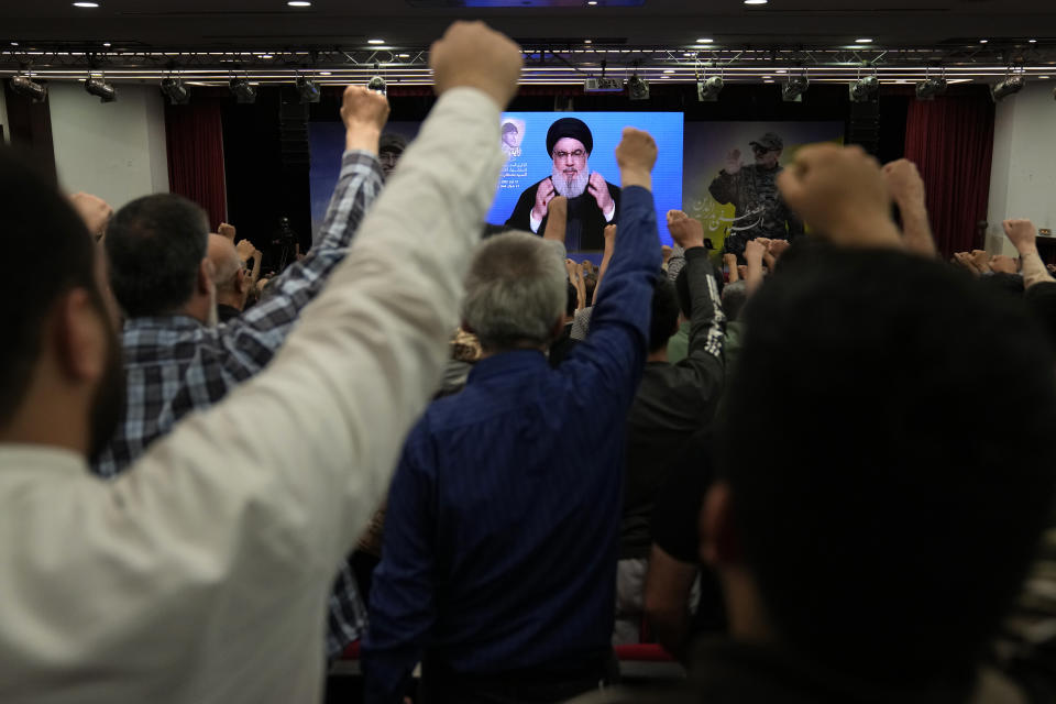 Supporters of the Iranian-backed Hezbollah group raise their fists and cheer as Hezbollah leader Sayyed Hassan Nasrallah greets them via a video link, during a ceremony to mark the seven anniversary death of Hezbollah slain top commander Mustafa Badreddine, in the southern suburbs of Beirut, Lebanon, Friday, May 12, 2023. Nasrallah denied Friday reports that linked one of Syria's most well-known drug dealers who was killed earlier this week in an airstrike near the Jordanian border to the Iran-backed group calling such accusations "baseless lies." (AP Photo/Hussein Malla)