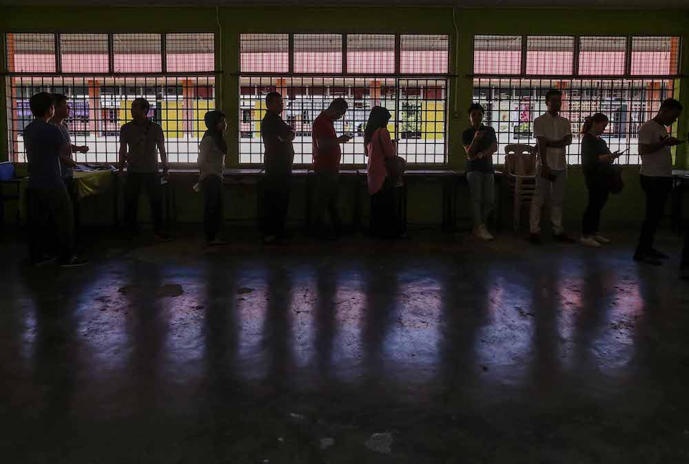 Voters queue to cast their votes outside a polling station during the 14th general elections in SMK Sri Muar, Muar May 9, 2018. — Picture by Firdaus Latif