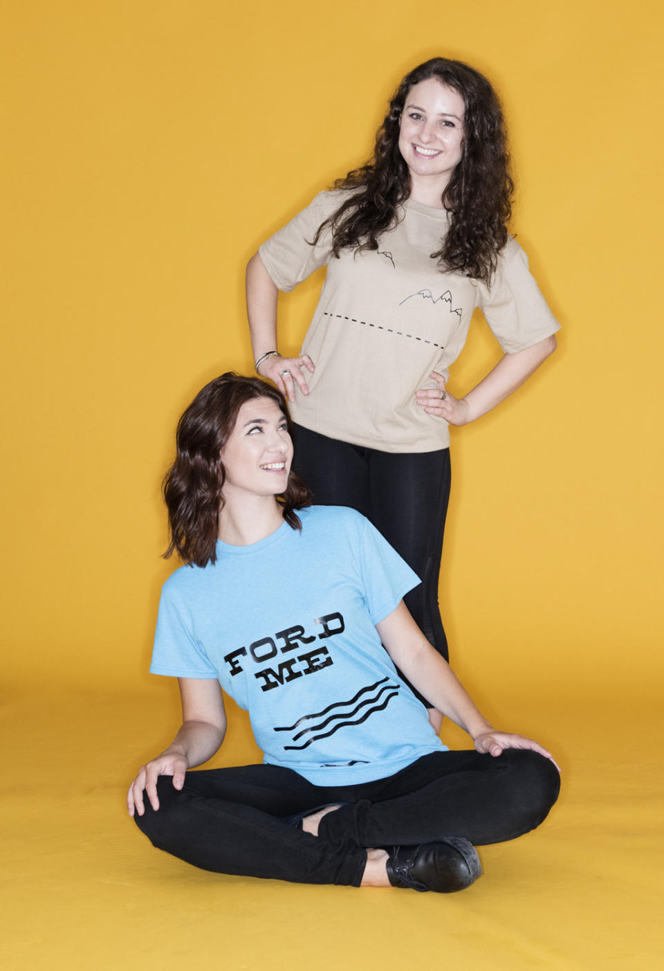 Seated woman wearing a "Ford Me" T-shirt next to a woman wearing a hilly T-shirt