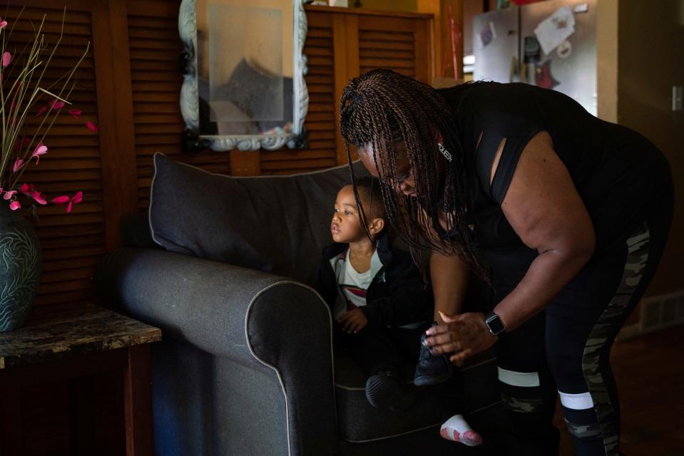 Tenai Leali, 47, of Detroit, puts shoes on her son Josiah Sims, 2, before going outside their home in Detroit on Sept. 27, 2022.