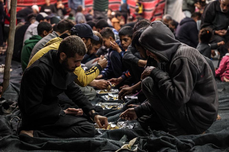 Palestinians share an iftar meal, the breaking of fast, on the first day of the Muslim holy fasting month of Ramadan, at a camp for displaced people in Rafah in the southern Gaza Strip on March 11, 2024, amid ongoing battles between Israel and the militant group Hamas.