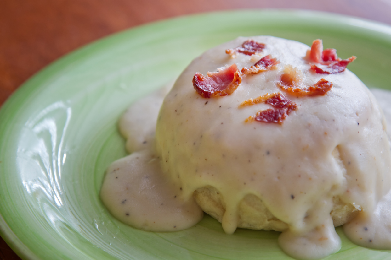 Biscuits and Gravy Topped With Bacon on a Green Plate, Selective Focus