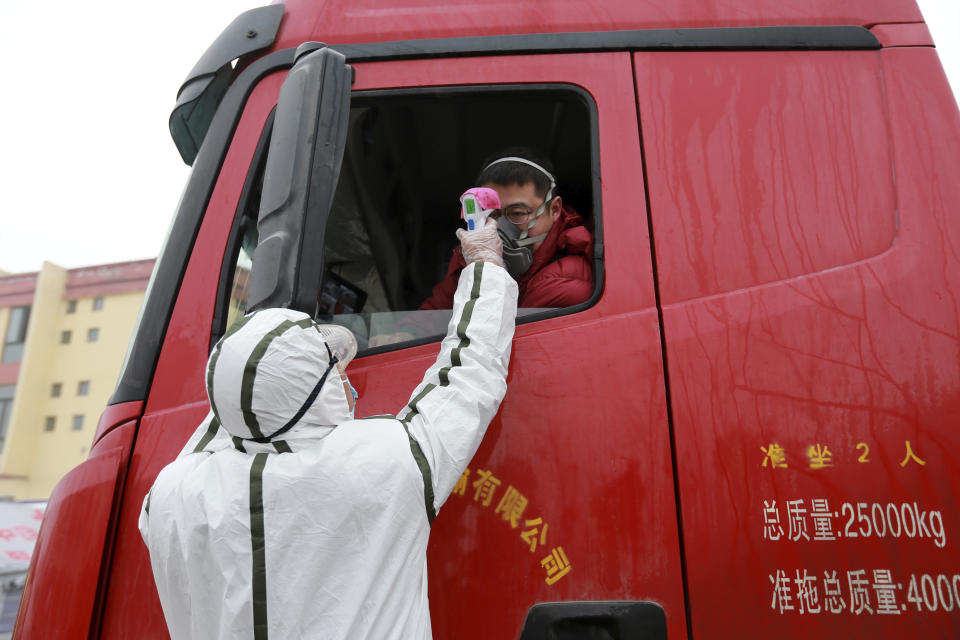 A worker in a hazardous materials suit takes the temperature of a truck driver at a checkpoint in Huaibei in central China's Anhui Province, Monday, Jan. 27, 2020. China on Monday expanded sweeping efforts to contain a viral disease by extending the Lunar New Year holiday to keep the public at home and avoid spreading infection as the death toll rose to 80. (Chinatopix via AP)