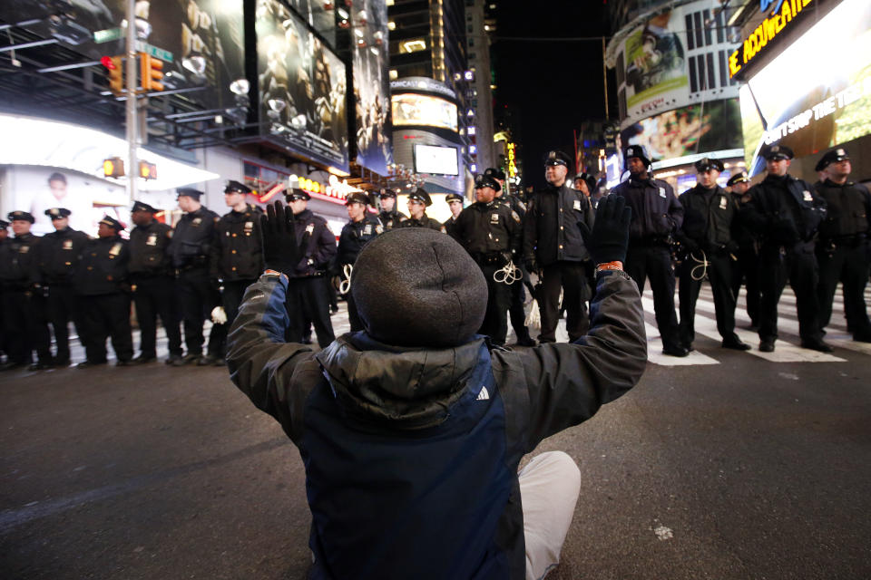 A protester sits in the road while rallying against a grand jury's decision not to indict the police officer involved in the death of Eric Garner encountering a line of police as they make their way west on 42nd Street near Times Square, Thursday, Dec. 4, 2014, in New York. (AP Photo/Jason DeCrow)
