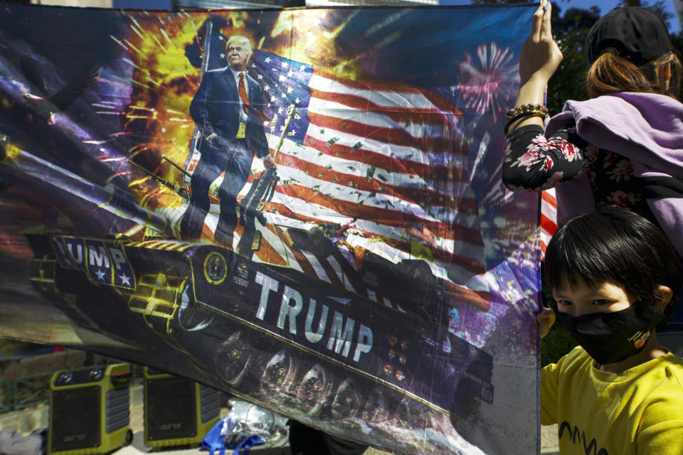 A masked child holds a flag baring a picture of U.S. President Donald Trump during a rally in Hong Kong, Sunday, Dec. 1, 2019. China accused the U.N. high commissioner for human rights of emboldening "radical violence" in Hong Kong by suggesting the city's leader conduct an investigation into reports of excessive use of force by police. The back and forth came ahead of three marches on Sunday in the semi-autonomous Chinese territory. (AP Photo/Ng Han Guan)