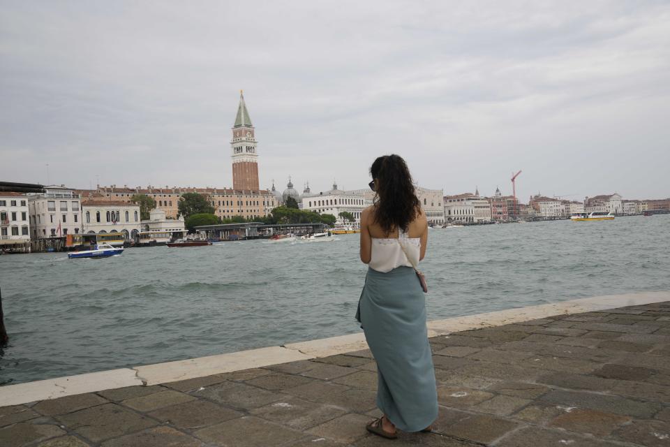 A tourist stands in front of St Mark's square in Venice, Italy, Wednesday, Sept. 13, 2023. The Italian city of Venice has been struggling to manage an onslaught of tourists in the budget travel era. The stakes for the fragile lagoon city are high this week as a UNESCO committee decides whether to insert Venice on its list of endangered sites. (AP Photo/Luca Bruno)