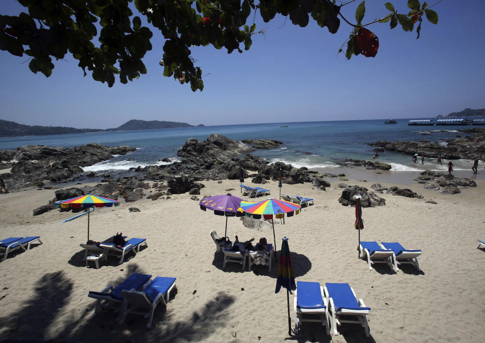 In this March 13, 2014 photo, tourists spend time on Patong Beach in Phuket province, southern Thailand. Thailand’s sapphire blue waters, wildlife parks, delicious cuisine and raunchy red light districts have attracted tourists for decades. Phuket is one of Thailand’s tourism honeypots. Tourists flock here in droves each year for its sun, sand and laid back ambience. And some lose their passports along the way. (AP Photo/Sakchai Lalit)