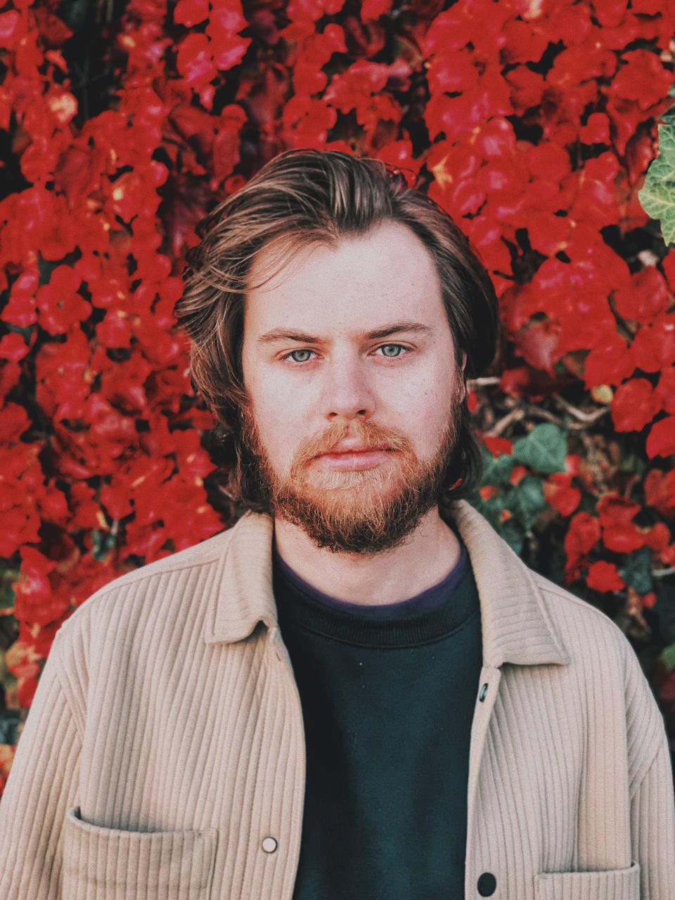 Man standing in front of floral background 