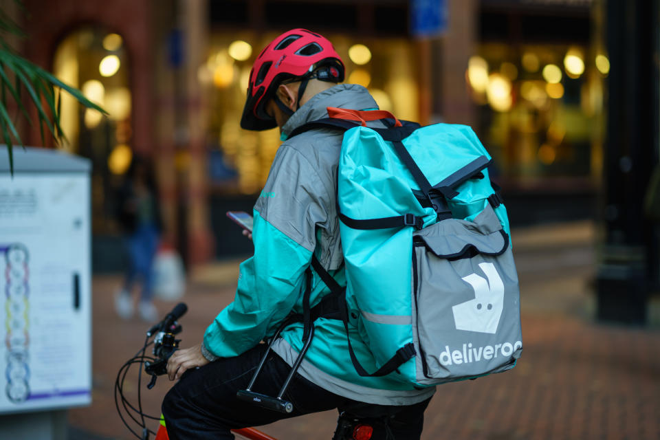 Coventry, UK - October 18, 2018 - Delivery food courier guy from Deliveroo checking order via mobile phone.