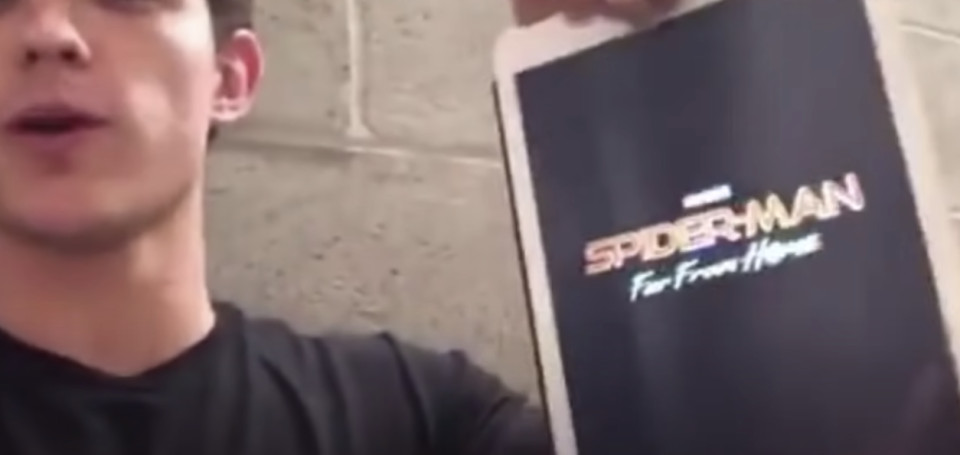 Tom Holland holding up an ipad that says "spider-man: far from home)