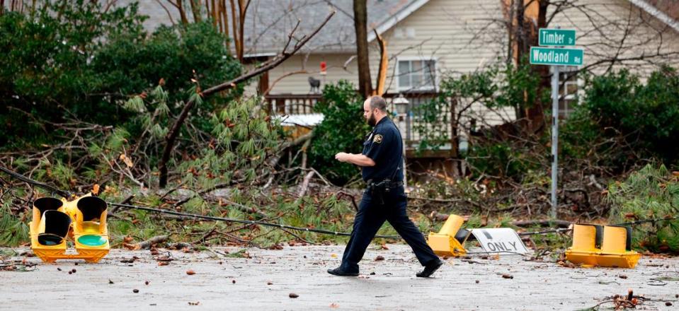 Garner police walk by downed limbs and street lights at Woodland Road and Timber Drive in Garner, N.C. after a storm passed through Sunday, Dec. 10, 2023.