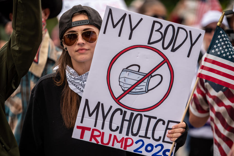 Una manifestante durante una protesta contra el confinamiento en Austin, Texasm el 18 de abril, con un cartel en el que se puede leer su rechazo al uso de la mascarilla con el mensaje "Mi cuerpo, mi elección". (Photo by Sergio Flores/Getty Images)