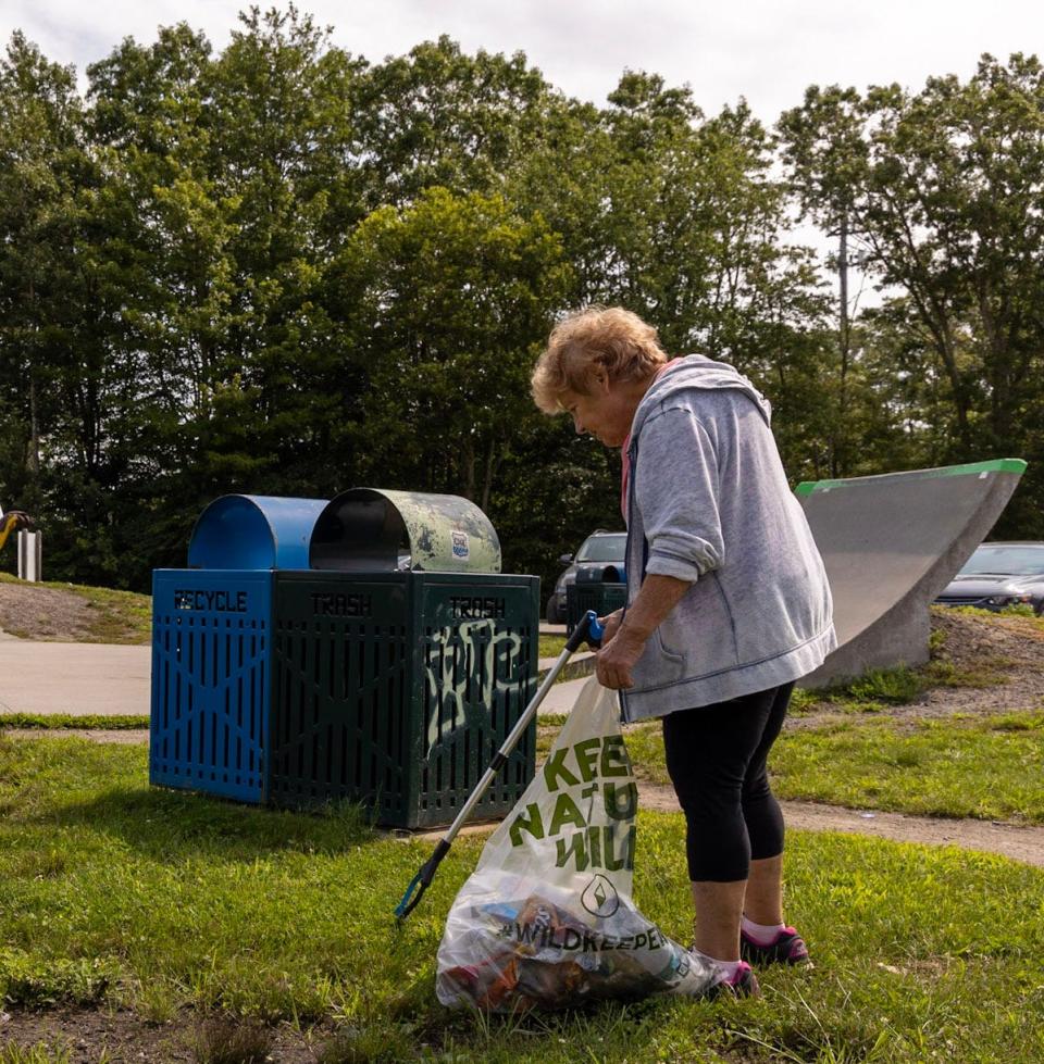 Tiverton Litter Committee Member Joyce Andrews at a past clean-up event in Tiverton. The bag reads "Keep Nature Wild."