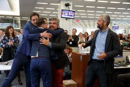 New York Times photographers Daniel Etter, Sergey Ponomarev, Mauricio Lima and Tyler Hicks (L-R) react as they are applauded by their colleagues in the newsroom after winning the 2016 Pulitzer Prize for Breaking News Photography in New York, April 18, 2016. The Times shared the award with Thomson Reuters for their images of the migrant crisis in Europe. REUTERS/Richard Perry/The New York Times/Handout via Reuters