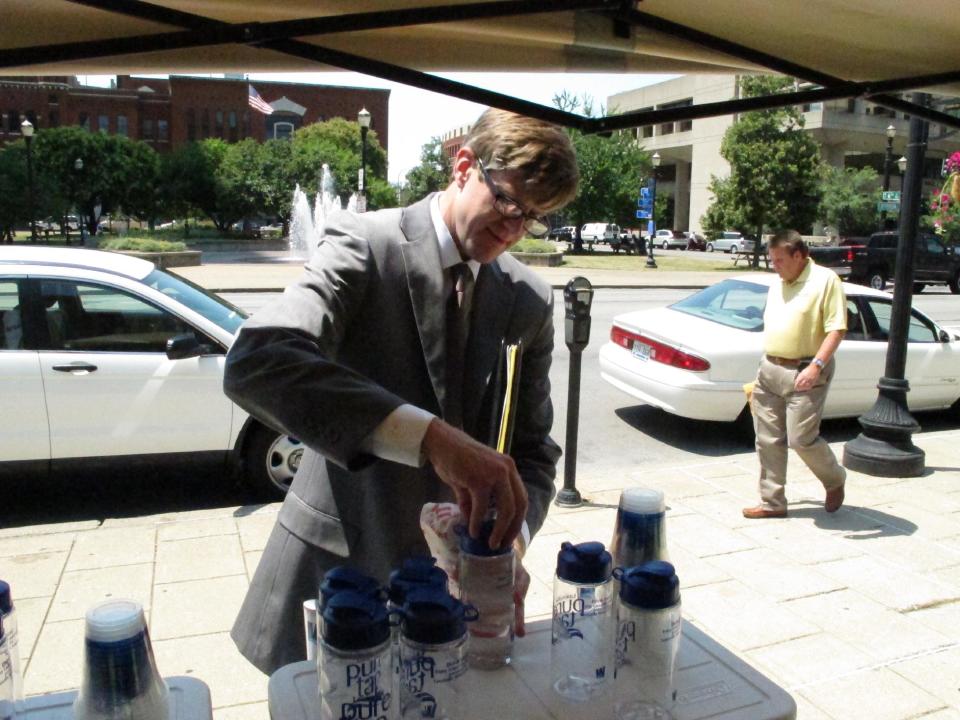 Nick Neumann puts the lid on a bottle of water drawn from the tap on Thursday, June 28, 2012, in Louisville, Ky., during a midday break. The free water was offered by Louisville Water Co. to help people keep hydrated as temperatures soared. (AP Photo/Bruce Schreiner)