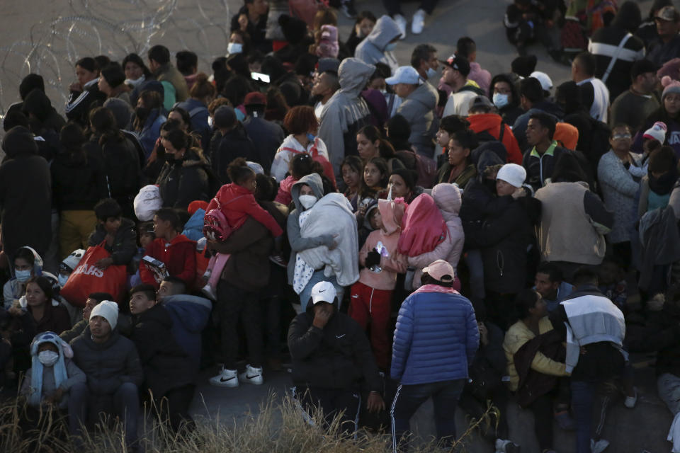 Migrants stand behind barbed wire to keep them from crossing into El Paso, Texas, as seen from Ciudad Juarez, Mexico, Tuesday, Dec. 20, 2022. Tensions remained high at the U.S-Mexico border Tuesday amid uncertainty over the future of restrictions on asylum-seekers, with the Biden administration asking the Supreme Court not to lift the limits before Christmas. (AP Photo/Christian Chavez)