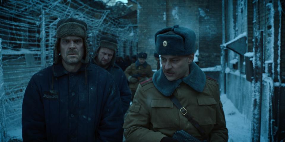 Jim in a Russian-style hat (with ear flaps) in an icy, prisonlike setting