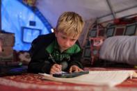 Internally displaced boy, Mahmoud Abdel Hadi, 8, studies inside his tent in Atmeh camp