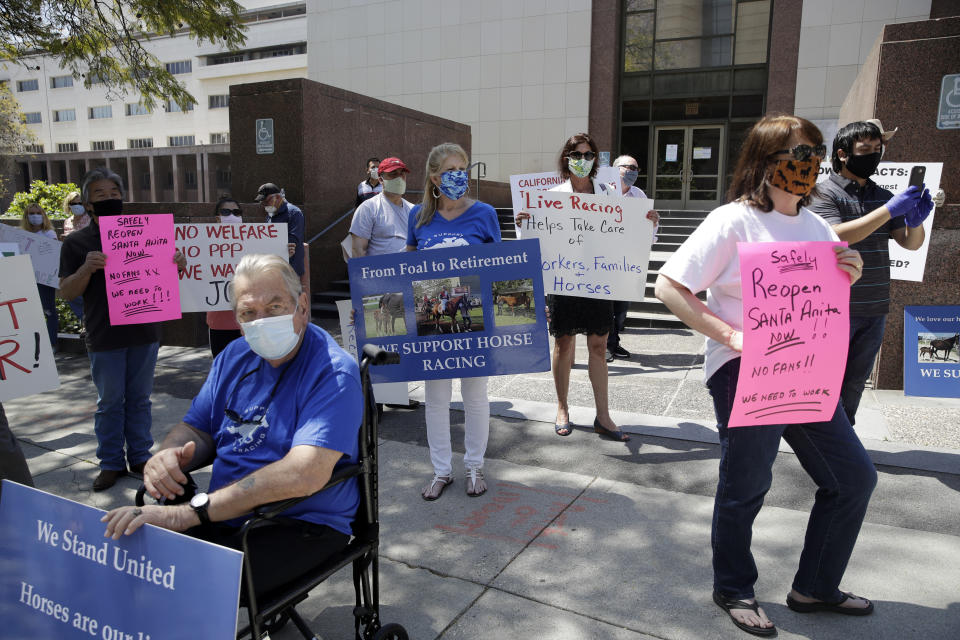 Horse racing supporters stand outside the Board of Supervisors building to protest the closing of Santa Anita Park as part to the state's stay-at-home measures amid the COVID-19 pandemic Tuesday, April 28, 2020, in Los Angeles. (AP Photo/Marcio Jose Sanchez)