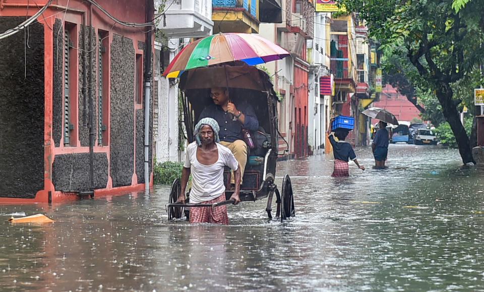 <div class="paragraphs"><p>A hand rickshaw-puller carries a passenger through a waterlogged city road after heavy rains in Kolkata.</p></div>