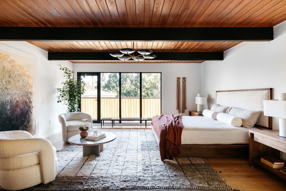dormitorio con dos butacas frente a la cama y techo de lamas de madera
