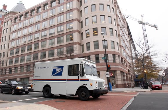 A U.S. Postal service truck driving down a city street.