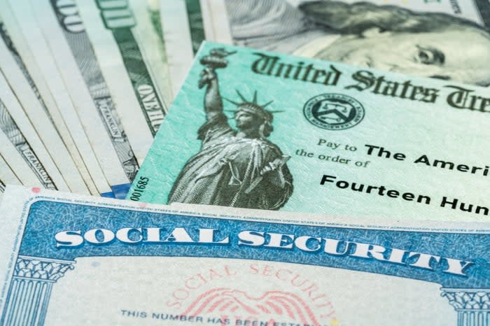 A Social Security card laid atop a U.S. Treasury check and U.S. currency.