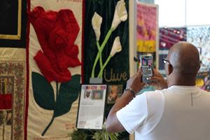 A visitor takes a picture of the AIDS Memorial Quilt, which will be in Louisiana for free community displays and events Feb. 7-11, 2023 as part of Changethepattern.org to honor and share the stories of Black and Brown lives lost to AIDS. Source: National AIDS Memorial.