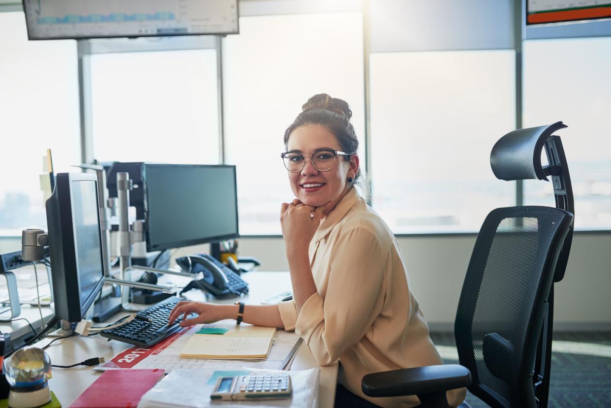 Smile, woman and desk for notes, computer and paperwork with calculator in office for finance. Accounting, money and female person for budget with