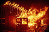 Flames shoot from a home as the Bear Fire burns through the Berry Creek area of Butte County, Calif., on Wednesday, Sept. 9, 2020. The blaze, part of the lightning-sparked North Complex, expanded at a critical rate of spread as winds buffeted the region. (AP Photo/Noah Berger)