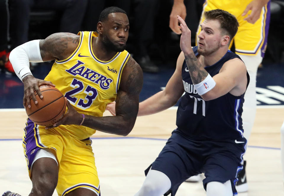 LeBron James #23 of the Los Angeles Lakers dribbles the ball against Luka Doncic #77 