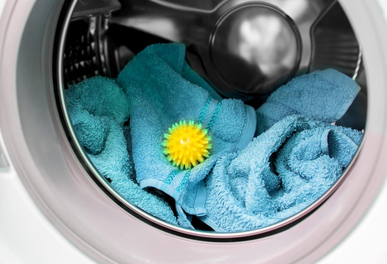 Using pvc dryer balls is natural alternative to both dryer sheets and liquid fabric softener, balls help prevent laundry from clumping in the dryer. Yellow spiky ball between blue soft bath towels.
