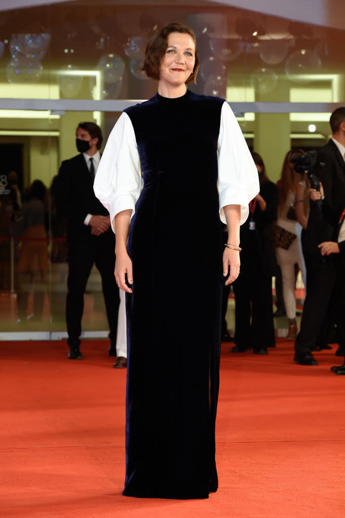 Maggie Gyllenhaal in a navy plush velvet gown with white sleeves on the red carpet for "The Lost Daughter"