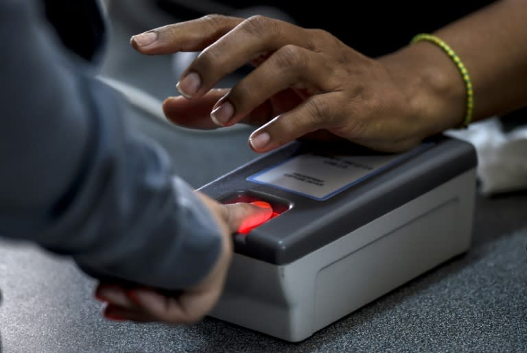 A woman presses a finger on a scanner during the authentication procedure of her signature for a recall referendum, in Caracas on June 24, 2016