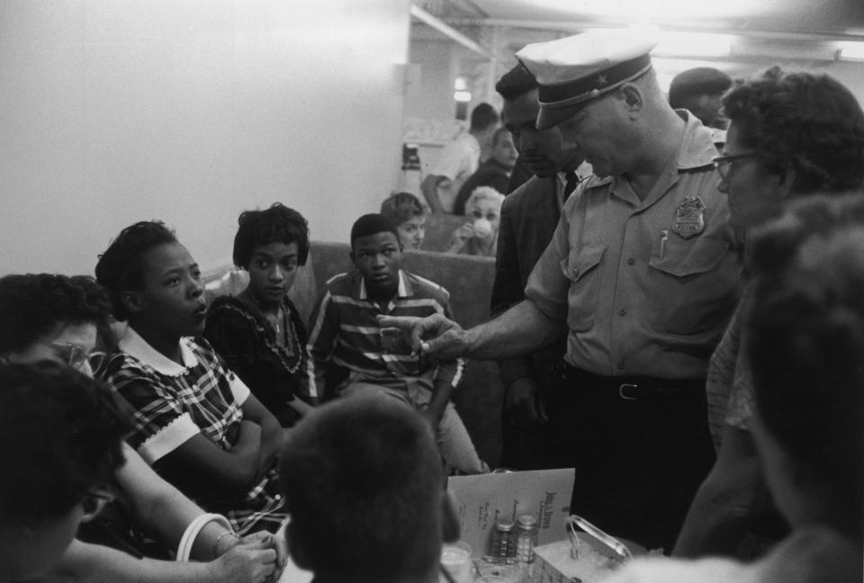 1958: A Caucasian policeman speaks with African-American protesters during a sit-in at Brown's Basement Luncheonette, Oklahoma. 