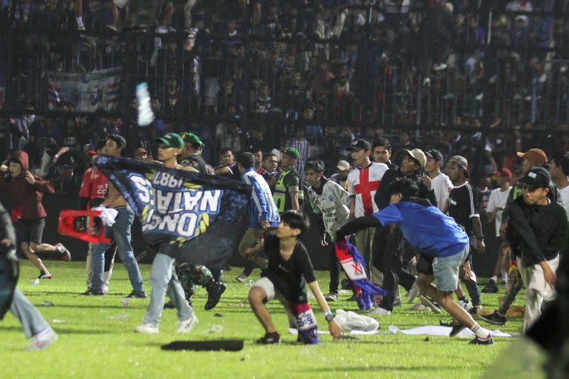 Los seguidores del Arema FC entran en el campo después de que el equipo al que apoyan perdiera contra el Persebaya tras el partido de fútbol de la BRI Liga 1 en el estadio Kanjuruhan, Malang, provincia de Java Oriental