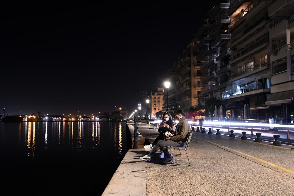 A couple wearing face masks against the spread of the coronavirus, sit on a bench during the lockdown to contain the spread of COVID-19 in the northern city of Thessaloniki, Greece, Tuesday, Nov. 3, 2020. A lockdown has come into effect in northern Greece, with the southeastern European country joining the list of the continent's nations tightening restrictions to restrain rapidly increasing coronavirus infections. (AP Photo/Giannis Papanikos)