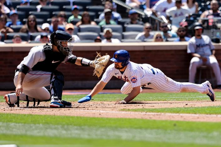 New York Mets' J.D. Davis slides ahead of the tag by Miami Marlins catcher Jacob Stallings to score during the fourth inning of a baseball game, Monday, June 20, 2022, in New York.