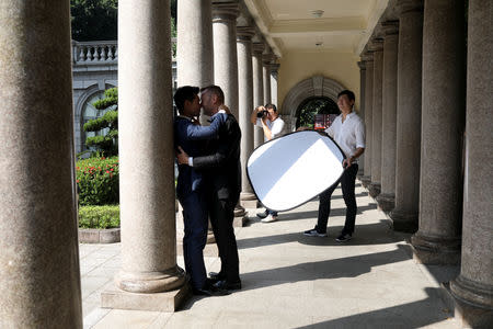 Lin Chinxuan (R), 29, holds a reflector as Austin Haung, 32, photographs Kao Shaochun (L) and John Sugden during their pre-wedding photoshoot in Taipei, Taiwan, November 11, 2018. REUTERS/Ann Wang