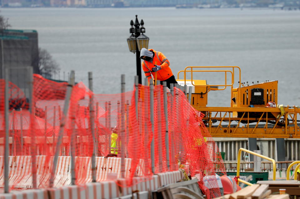 A construction worker climbs above a line of fencing at the site of a large public infrastructure reconstruction project of an elevated roadway and bridges in upper Manhattan in New York City, New York, U.S., April 22, 2021. REUTERS/Mike Segar