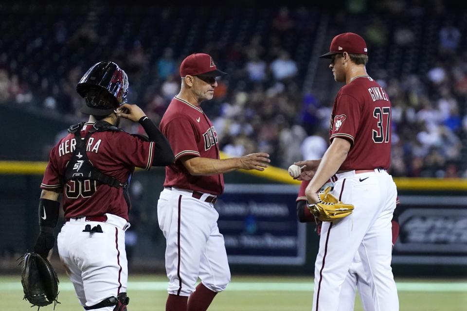 Arizona Diamondbacks manager Torey Lovullo, middle, takes the ball from Diamondbacks relief pitcher Kevin Ginkel (37) as Diamondbacks catcher Jose Herrera, left, looks on during the sixth inning of a baseball game against the Colorado Rockies Sunday, Aug. 7, 2022, in Phoenix. (AP Photo/Ross D. Franklin)