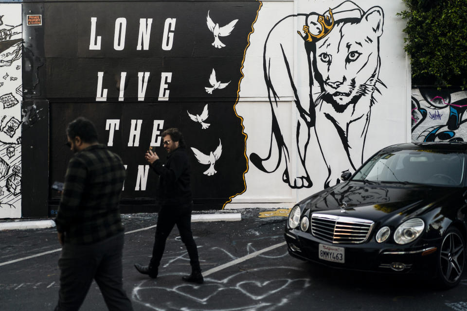 Two people walk past a mural by artist Corie Mattie depicting the famed mountain lion known as P-22 in Los Angeles, Friday, Jan. 20, 2023. The popular puma gained fame as P-22 and shone a spotlight on the troubled population of California's endangered mountain lions and their decreasing genetic diversity. But it's the big cat's death — and whether to return his remains to ancestral tribal lands where he spent his life — that could posthumously give his story new life. (AP Photo/Jae C. Hong)