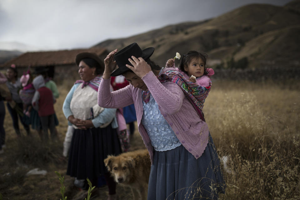 En imagen del 14 de agosto de 2018, una mujer cargando a su hija se prepara para colocar flores en la tumba de parientes que murieron a manos del ejército peruano en 1983, durante el entierro en el cementerio de Rosaspata, en la provincia peruana de Ayacucho. Científicos forenses en varios países de Latinoamérica siguen trabajando para identificar los restos de las personas que fueron asesinadas durante dictaduras militares y conflictos civiles registrados hace décadas.0 (AP Foto/Rodrigo Abd)