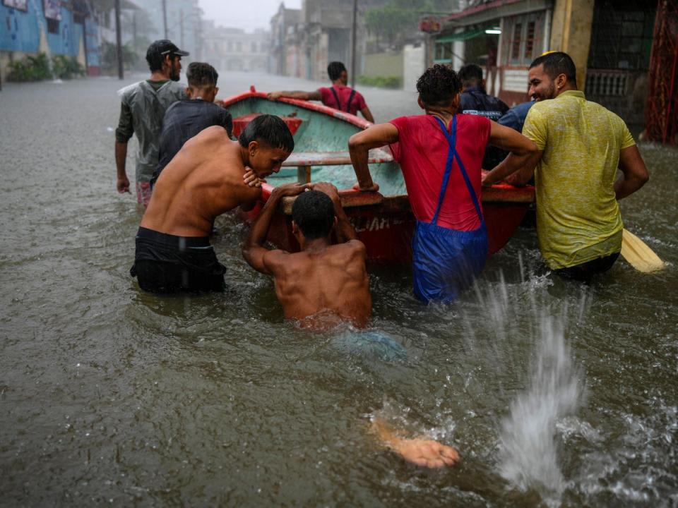 Volunteers push a boat through a flooded street to rescue a neighbour who cannot leave his home in Havana, Cuba, 3 June 2022 (AP Photo/Ramon Espinosa)