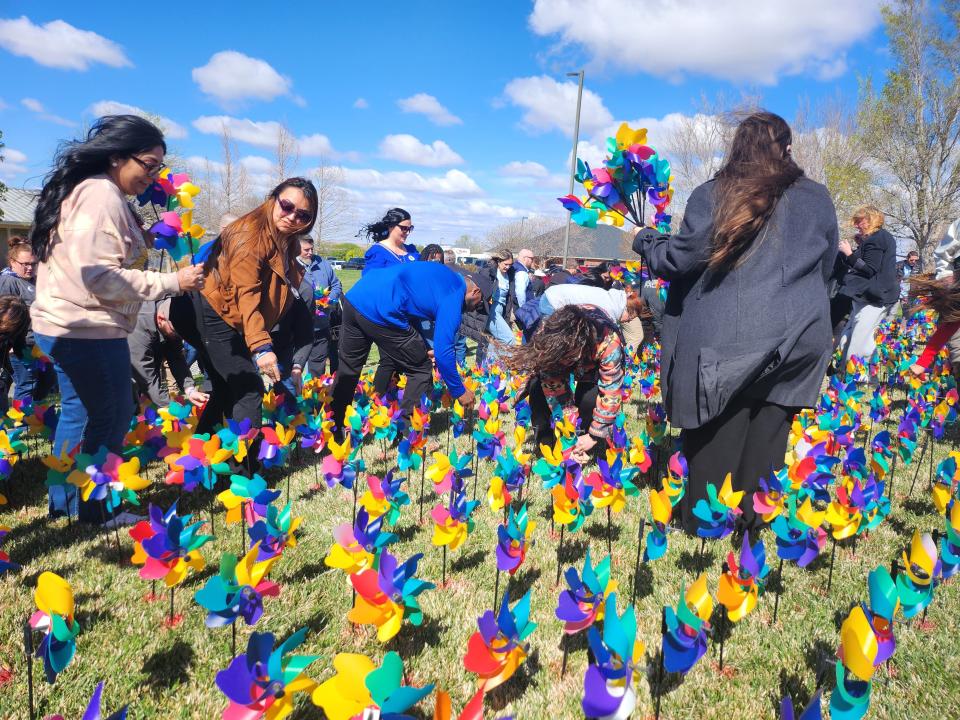Crowds of individuals representing area law enforcement, first responders, child care advocates, and more plant over 1,000 pinwheels on the front lawn of The Bridge Children's Advocacy Center to spread awareness for Child Abuse Prevention Month.