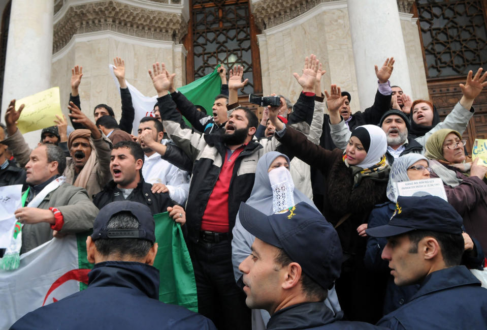 Police officers face protesters from the "Barakat!" ("Enough") group, during a rally against Algerian President Abdelaziz Bouteflika, Saturday, March 15, 2014 in Algiers. About 100 Algerian activists from a new anti-government movement staged a rare protest Saturday against the ailing president and his decision to run for a fourth term. Elections will take place on April 17, 2014. ( AP Photo/Ouahab Hebbat)