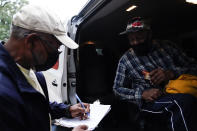 Neighborhood Assistance Corporations of America, employee, Malcom Williams, 65, of Loganville, Ga., left, works on paperwork for first time voter, Gary Ragland, 64, of East Point, Ga., for "Roll to the Polls" a daily event to help usher voters to the polls for early voting on Wednesday, Oct. 28, 2020, in East Point, Ga. (AP Photo/Brynn Anderson)
